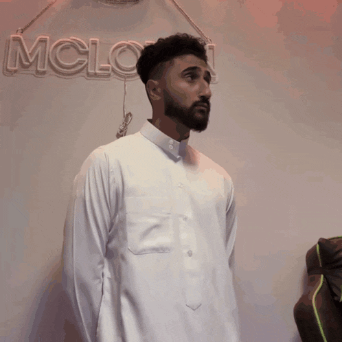 a man in a white shirt is standing in front of a neon sign that says mclown
