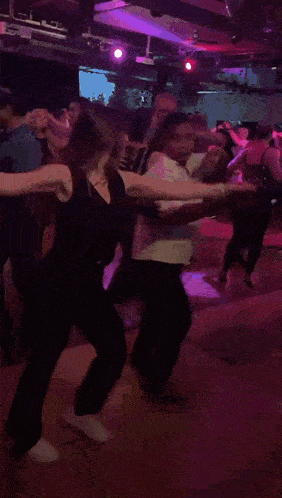 a group of people are dancing in a dark room