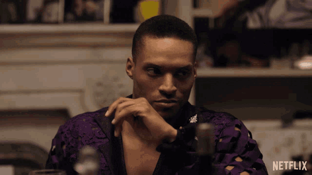 a man in a purple shirt sits in front of a netflix logo