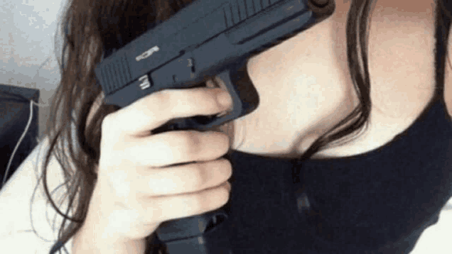 a woman in a black tank top is holding a gun with the letter u on it