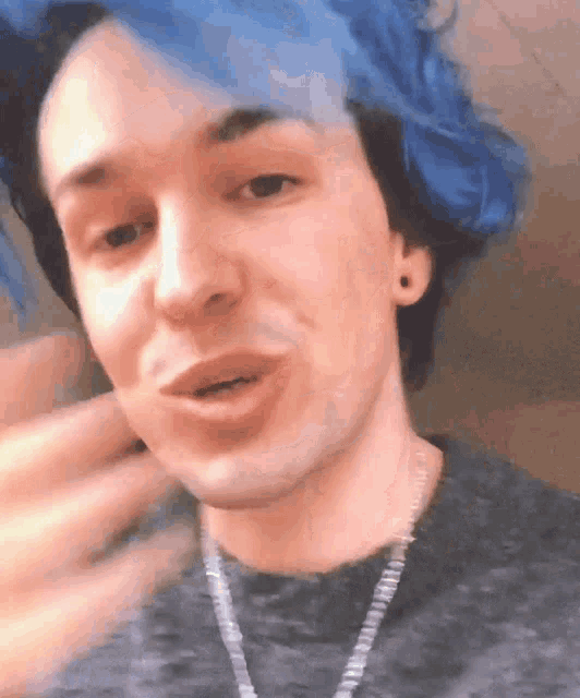 a young man with blue hair is wearing a necklace