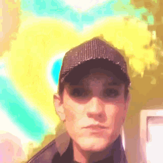 a man wearing a baseball cap and a jacket is making a funny face .