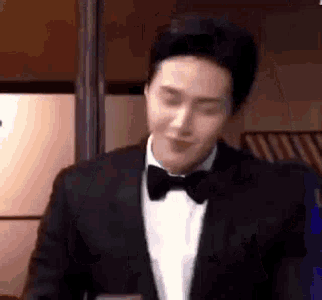 a man in a tuxedo and bow tie is standing in a room .