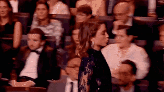 a woman in a blue dress is standing in front of a crowd of people in a theater .