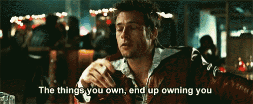 a man is sitting at a table with the words " the things you own end up owning you "