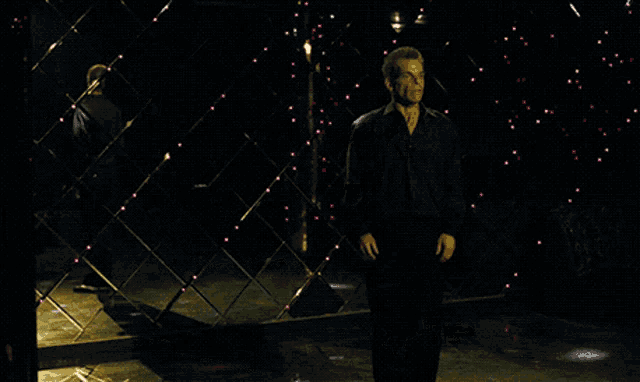 a man in a black jacket is standing in front of a wall with red lights on it