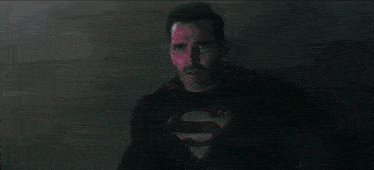 a man is smoking a cigarette in a dark room and smoke is coming out of his mouth .
