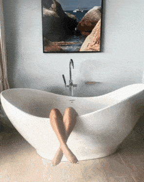 a woman 's legs are sticking out of a bathtub in a bathroom