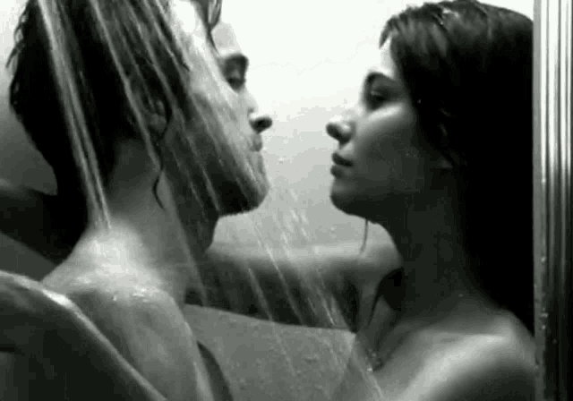 a man and a woman are taking a shower together and kissing .