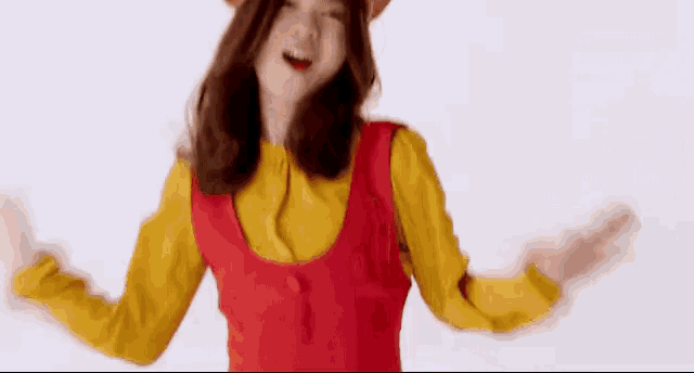 a woman in a red dress and yellow shirt is dancing with her arms outstretched and smiling .