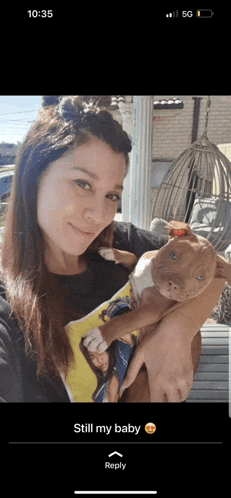 a woman is holding a brown and white puppy in her arms and the time is 10:35