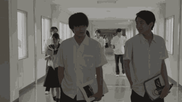 a group of people are walking down a hallway and one of them is holding a piece of paper that says " a "