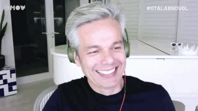 a man wearing headphones is smiling in front of a white piano ..