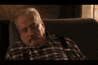 a man in a plaid shirt is sitting in a chair