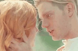 a man and a woman are touching their foreheads and smiling at each other .