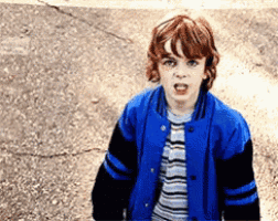a young boy with red hair wearing a blue and black jacket