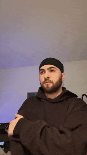 a man with a beard is wearing a black hat and a ring on his finger