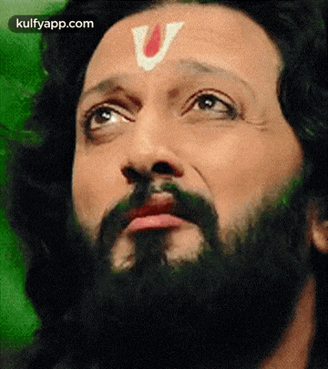 a close up of a man with a beard and a v on his forehead .
