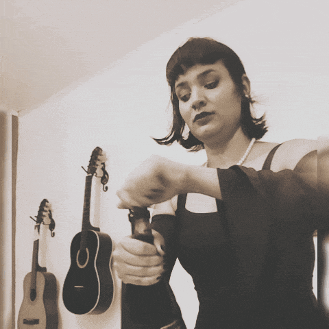 a woman in a black dress is holding a guitar with the letter o on it