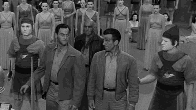 a black and white photo of a group of men and women standing next to each other .
