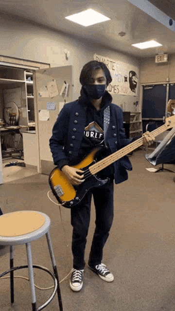 a man playing a bass guitar in front of a sign that says " exit "