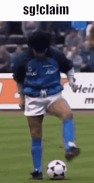 a man in a blue jersey is kicking a soccer ball on a soccer field .