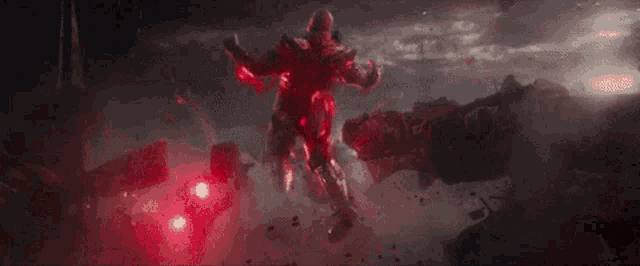 a man in a suit is standing in a dark room with red lights coming out of his arms .