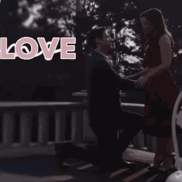 a man is kneeling down to propose to a woman with the words love love love behind him