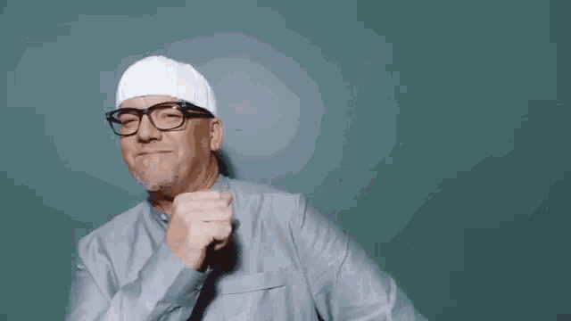 a man wearing glasses and a white hat is making a fist .