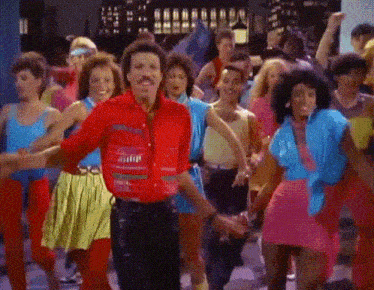 a man in a red shirt is surrounded by a group of people dancing