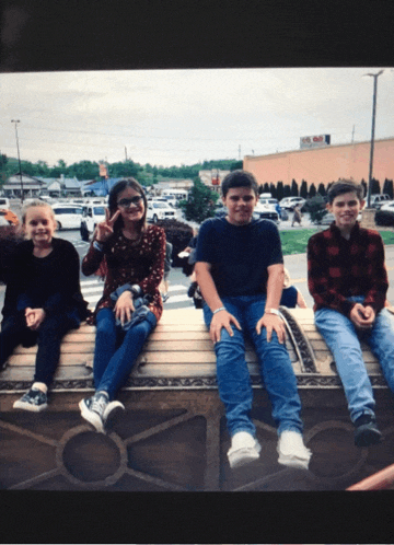 a group of young people sit on a bench in front of a building that says ' abc '