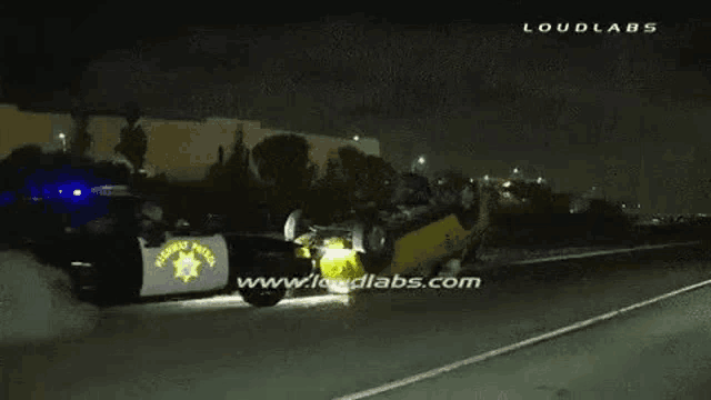 a police car is on its side on the side of a highway at night .