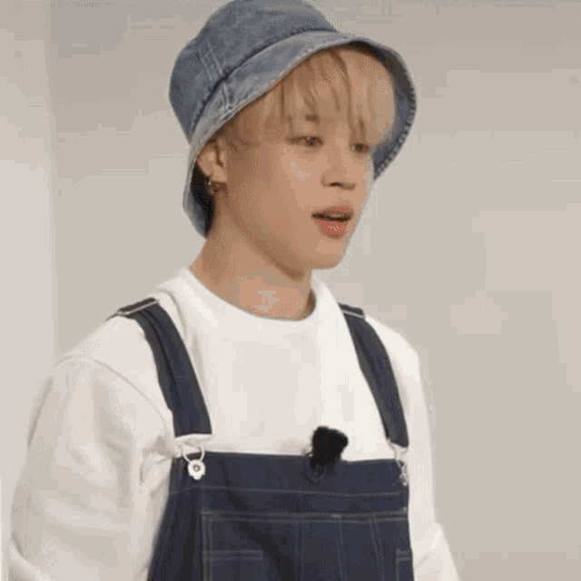 a man wearing overalls and a denim hat