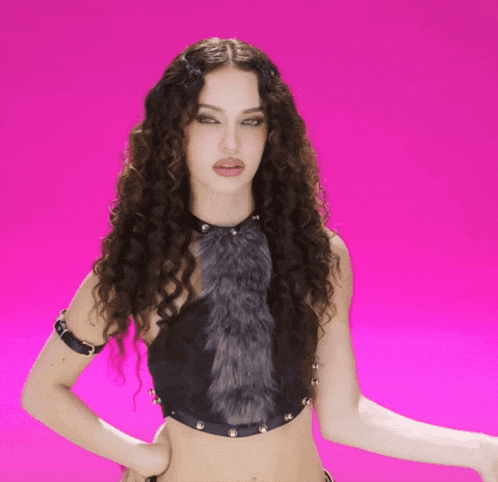 a woman with curly hair is wearing a black top with a fur trim