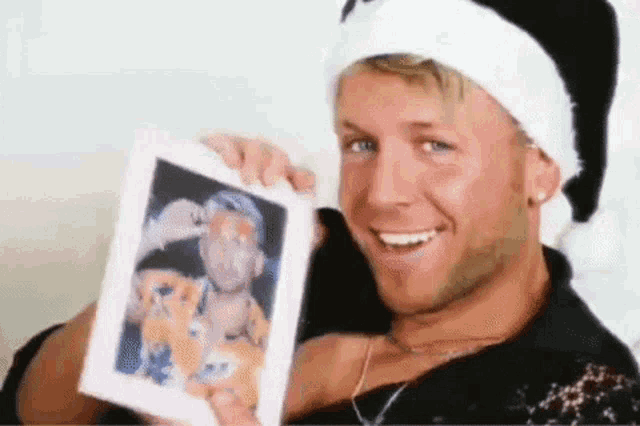 a man wearing a santa hat is holding a picture