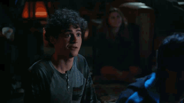 a young man with curly hair is looking at the camera