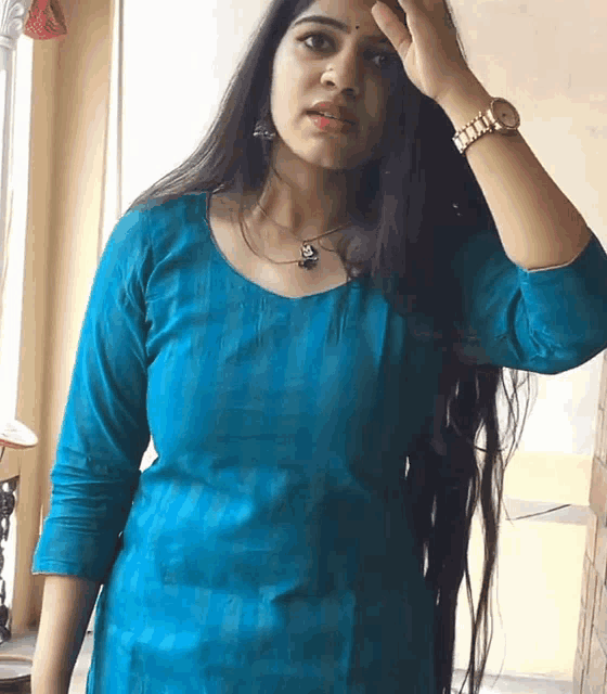 a woman with long hair wearing a blue dress and a watch on her wrist