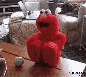 elmo the sesame street character is sitting on a table with his legs crossed