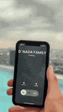 a person is holding a cell phone that says ' d nada family calling ' on the screen