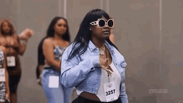 a woman wearing sunglasses and a denim jacket is standing in a line with other women .