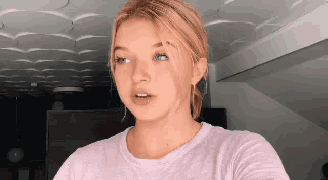 a girl with blonde hair is wearing a pink t-shirt