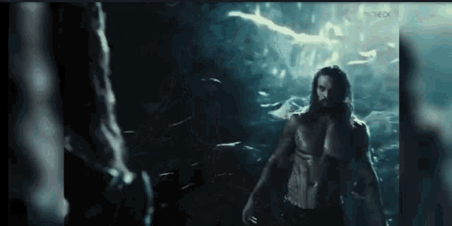 a man without a shirt is standing next to a woman in the water .