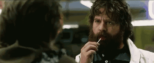 a man with a beard is holding a lollipop in his mouth .