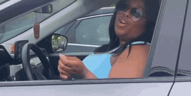 a woman wearing sunglasses is driving a car and talking on her cell phone .