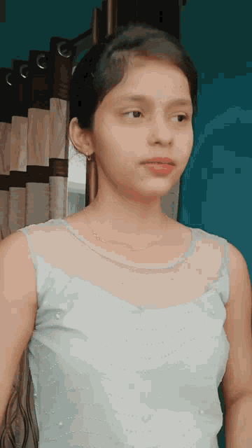 a young girl wearing a white top and a necklace