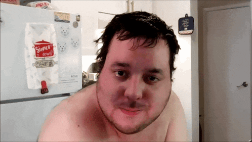 a man without a shirt is standing in front of a refrigerator that has a bag of snuggle monkeys on it