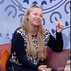 a woman in a leopard print shirt is sitting on a couch eating a sandwich .