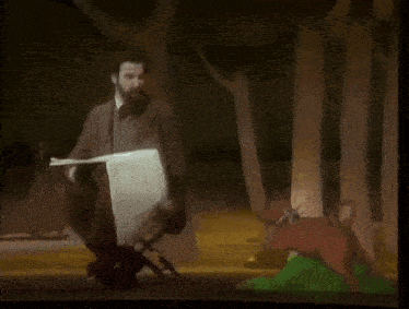 a man sits in a chair reading a book in a forest