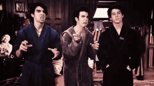 three men in bathrobes are standing in a dark room