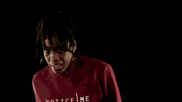 a person wearing a red ace me sweatshirt giving a peace sign